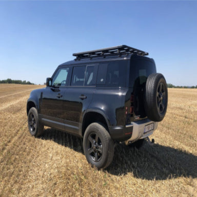 Eezi awn land rover defender roof rack on black suv rear side view in a field