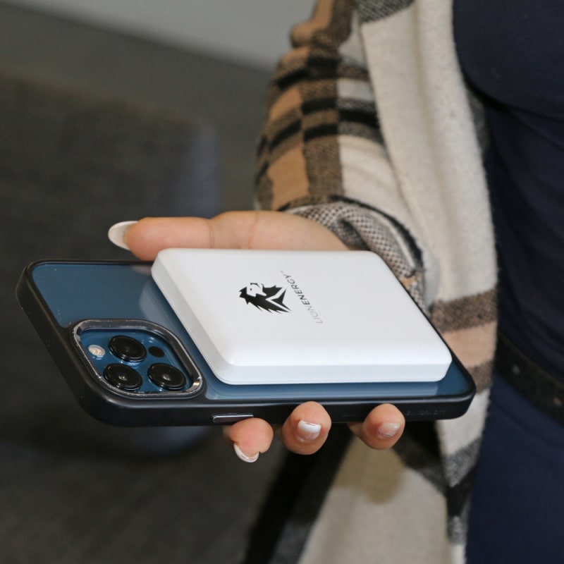 Lion claw portable power station in white with black logo on back of iPhone in a persons hand