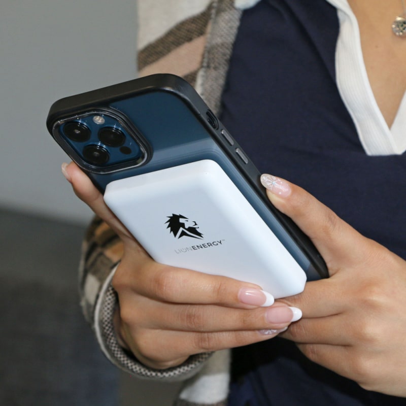 Lion claw power bank in white with black logo charging iphone while texting in a persons hand